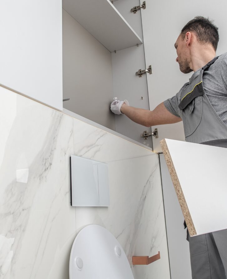 Bathroom remodeling contractor in Matthews, NC installing tile above a toilet.