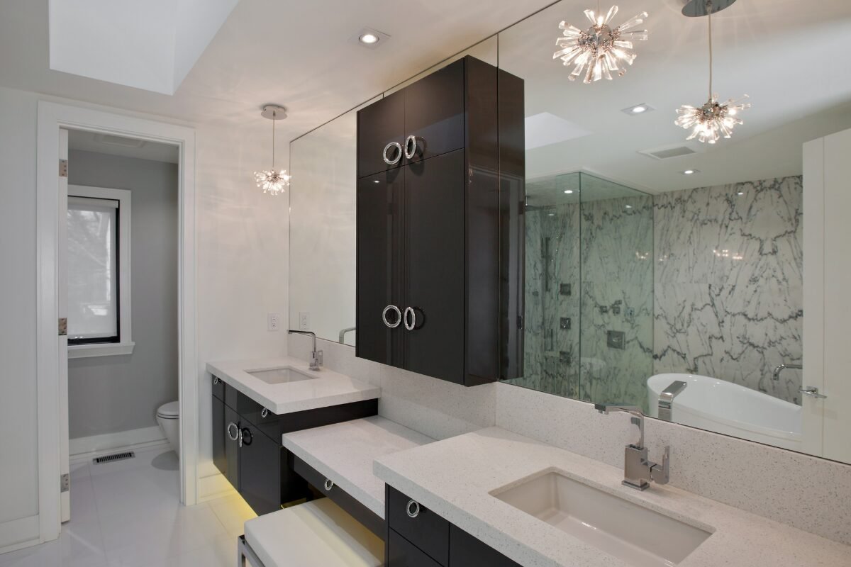 Spacious bathroom renovation in Mint Hill, NC with large vanity, dark wood cabinetry, and visible large glass walk-in shower with marble tile through the mirror.