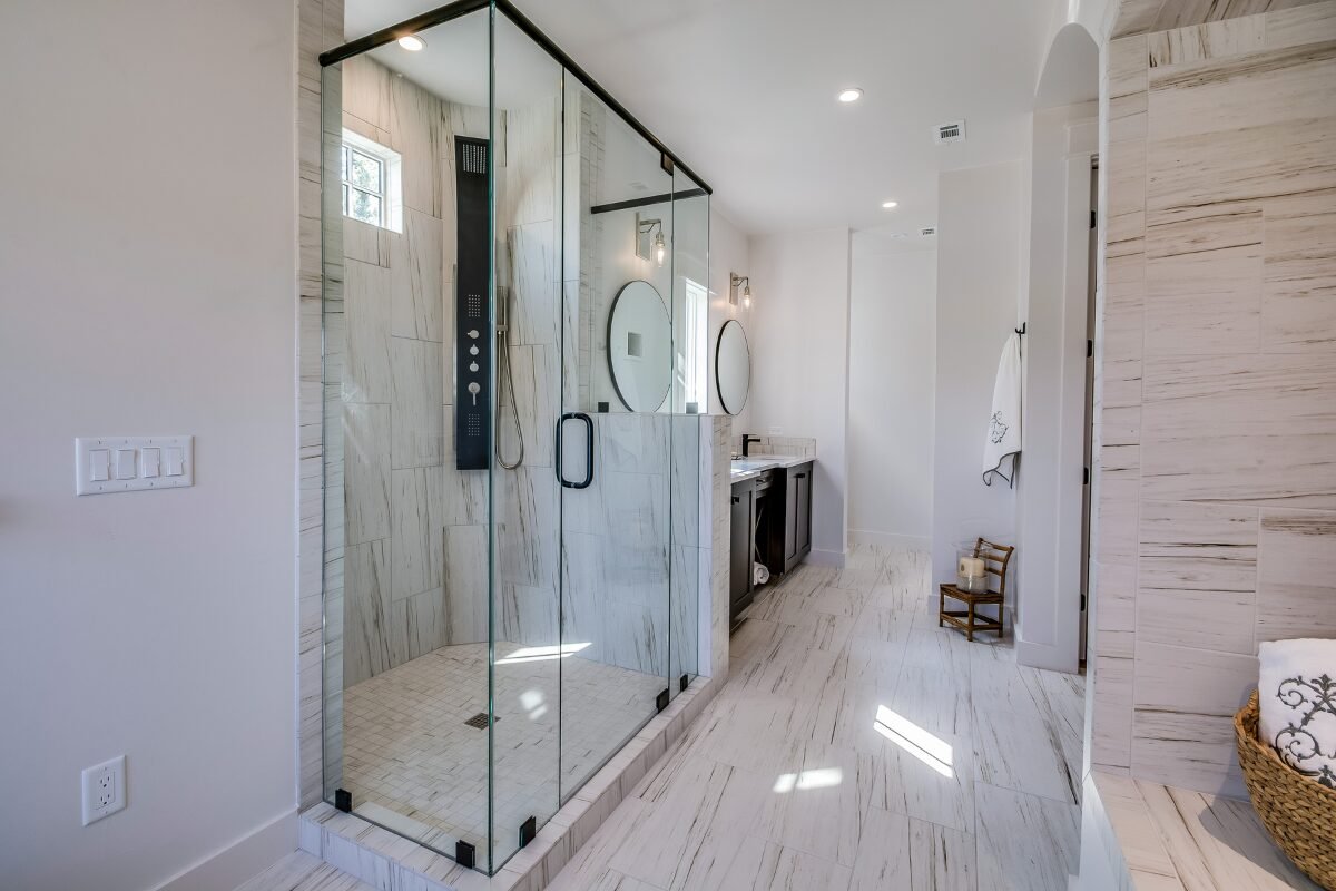 Modern glass walk-in shower with white tile floor in a Mint Hill, NC bathroom renovation.