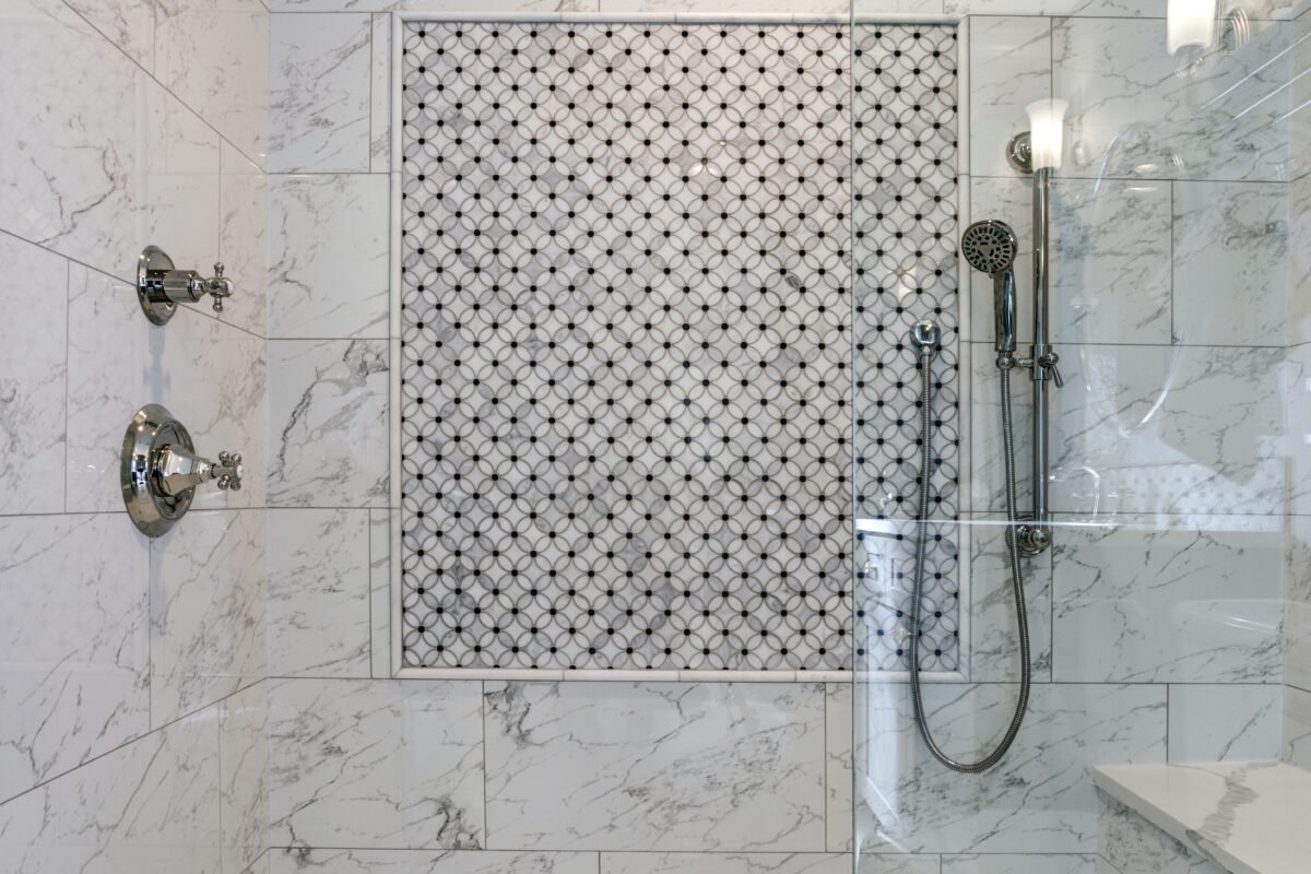 Close-up of a tiled shower remodel in Mint Hill, NC featuring Carrera marble.