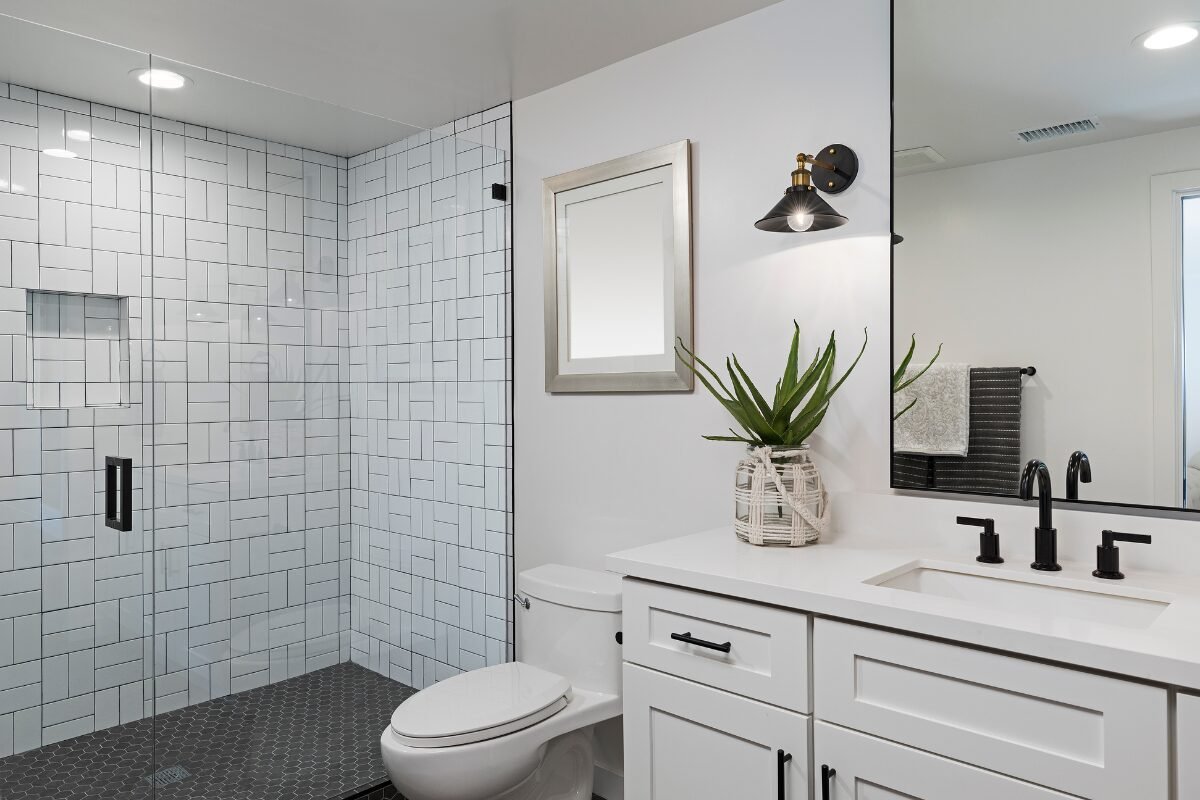 Shower with white tile walls and dark accent tiled floor in a Tub-to-Shower Conversion in Mint Hill, NC.